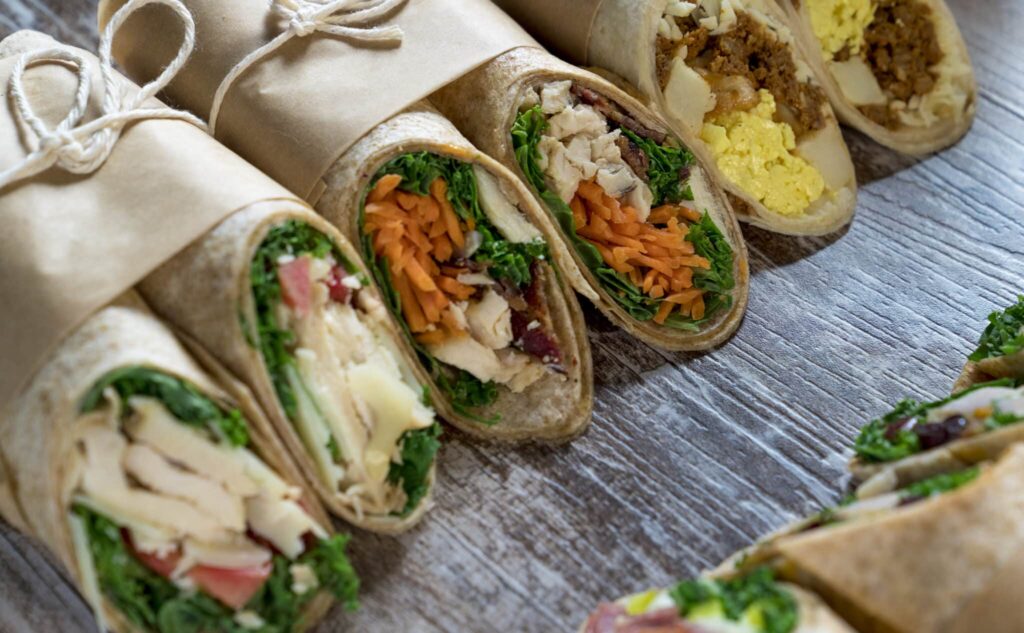 A variety of food wraps in brown paper on a wood backdrop