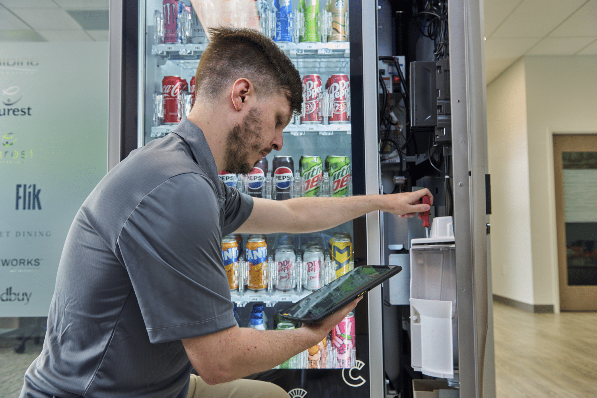 Canteen employee fixing a vending machine, vending technology maintenance, reliable vending service
