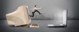 A man jumping from old desktop to new laptop