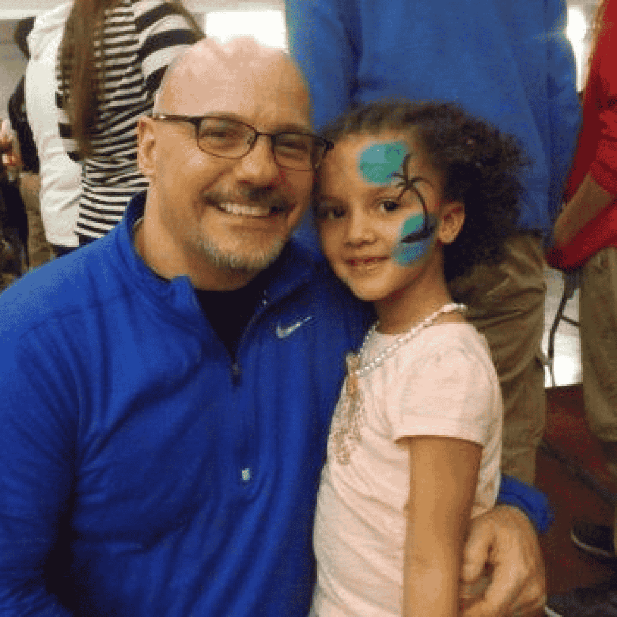Child with Face Paint Man hugging child with face paint and smiling