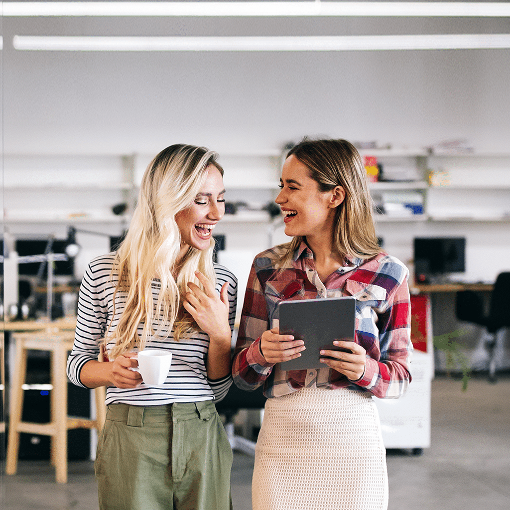 Two people walking around an office with coffee in hand