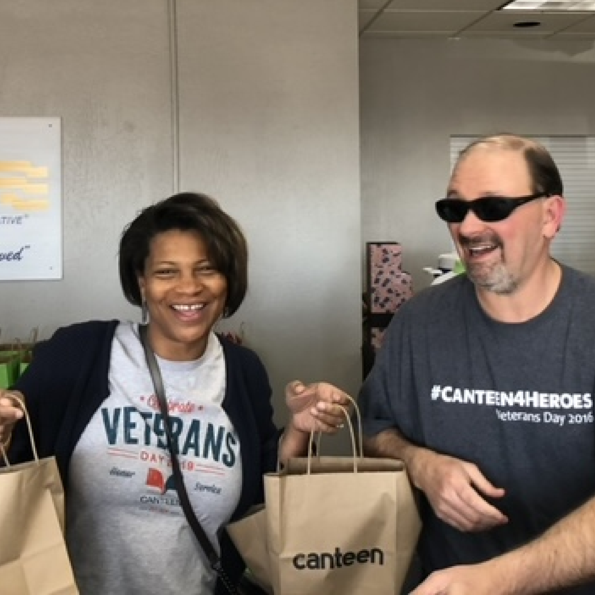 U.S. Vets People smiling with a Canteen veterans shirt, canteen bags