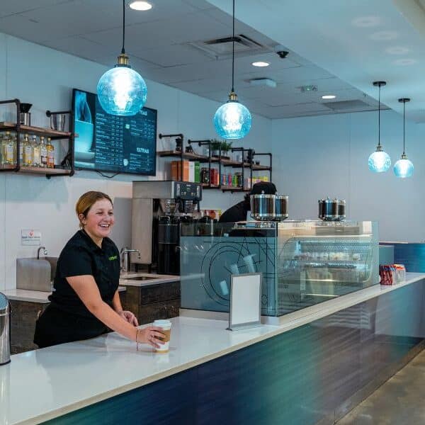Student barista serving coffee, student café, barista smiling with coffee, education setting