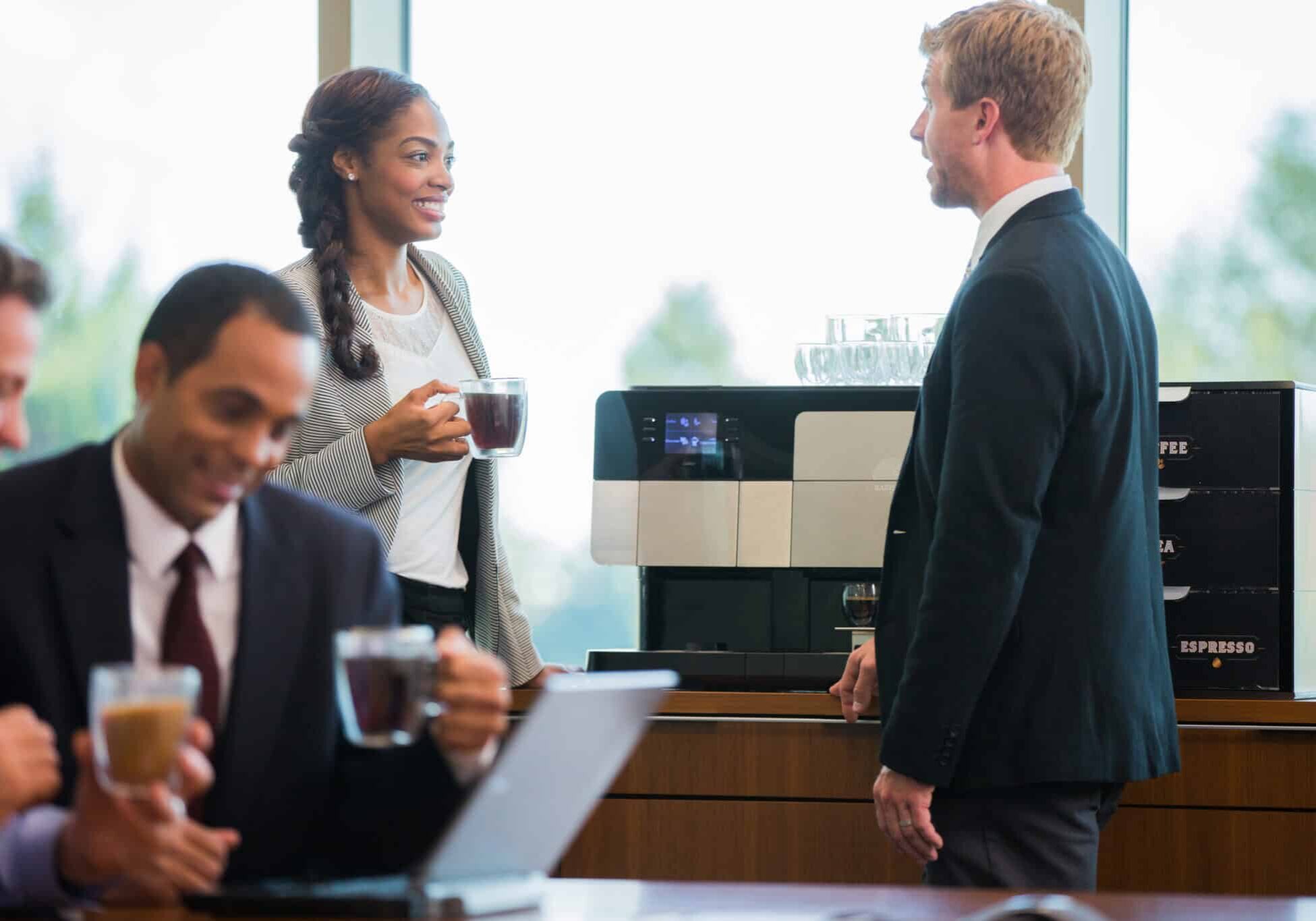 Two People Talking Over Office Coffee Finance workers talking with coffee, self-service coffee machine, office coffee equipment