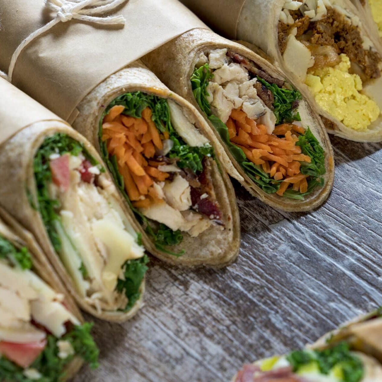 A variety of food wraps in brown paper on a wood backdrop