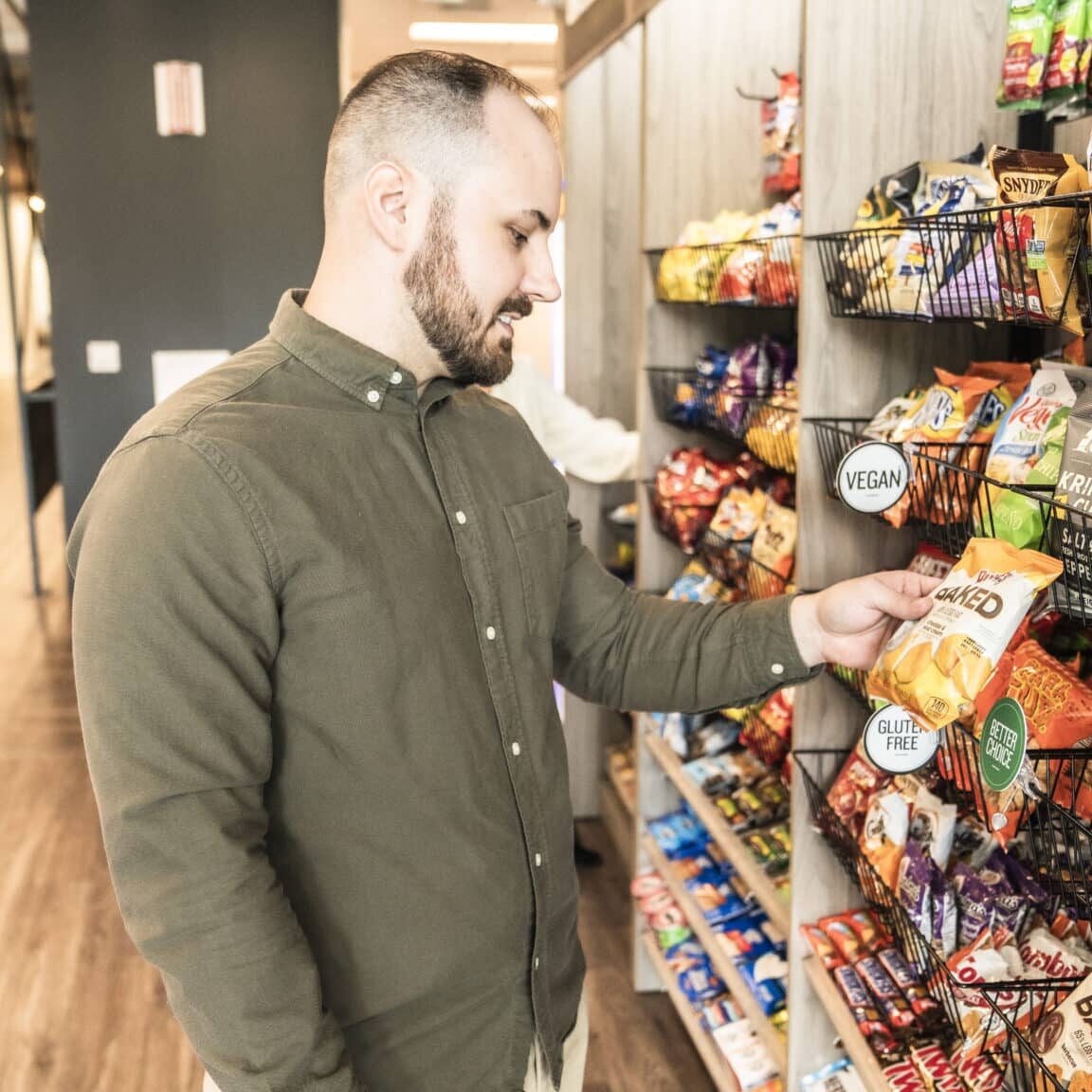 Man Contemplating at an Avenue C Person at a micro market deciding on a snack, micro market with snacks, indoor Avenue C