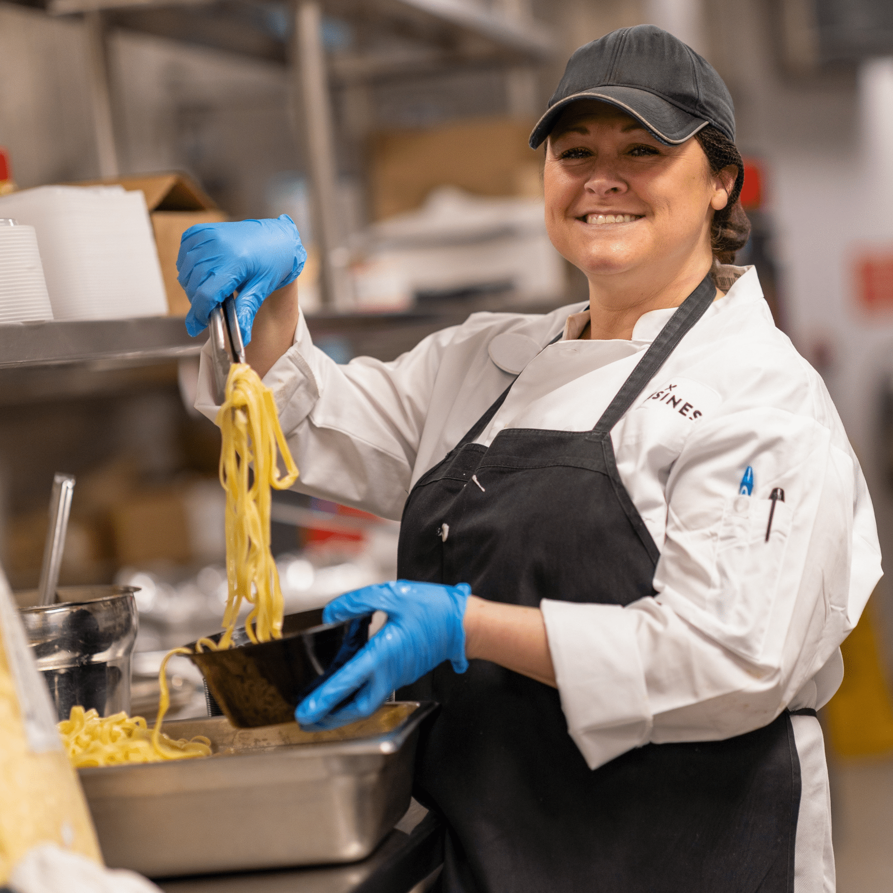 Cuisines Employee Cuisines employee smiling and making pasta in the kitchen